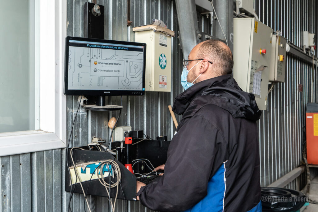Persona lavora al computer in ambiente industriale.