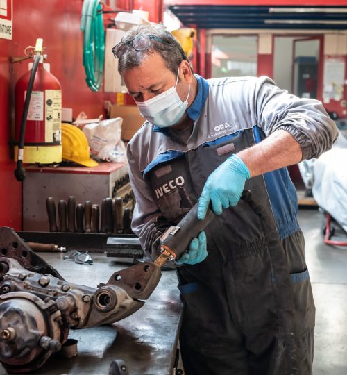 Meccanico lavora su un componente metallico in officina.